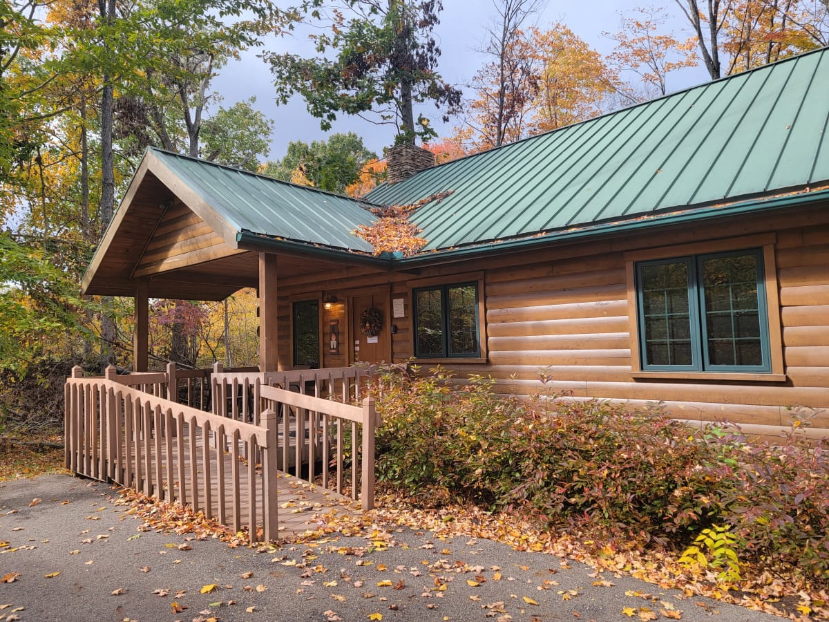 Cherry Blossom Cabin, a log cabin with a green roof and covered porch in the woods at Ferngully Creek near Millersburg, Ohio