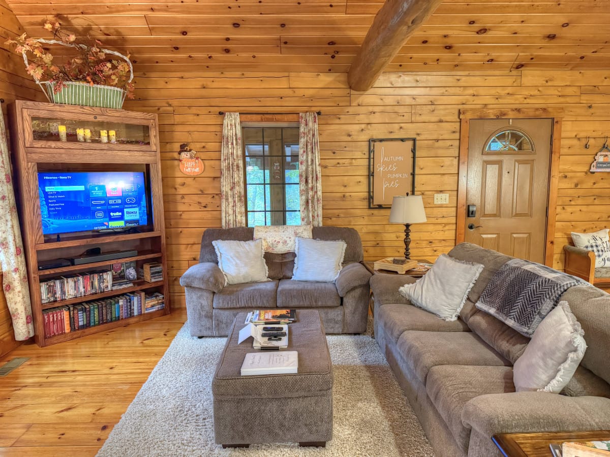 Cozy knotty-pine living room with a leather sofa inside Rosewood Cabin at Ferngully Creek